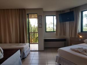 um quarto de hotel com duas camas e uma varanda em MARULHOS RESORT - STÚDIOS TEMPORADA em Porto de Galinhas