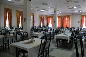 a dining room with tables and chairs and windows at Essentukskaya Klinika Sanatorium in Essentuki