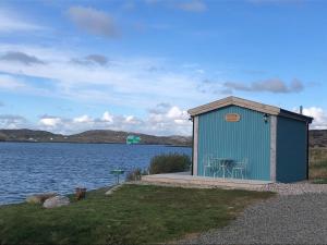 a blue building next to a body of water at Otter Bothy in Uig