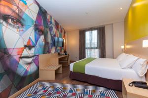 Habitación de hotel con cama y mural femenino en Hotel Gran Bilbao, en Bilbao