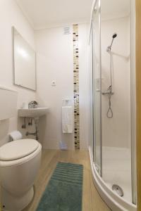a white bathroom with a toilet and a shower at Casas Do Mar in Ribamar