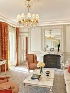 a living room with a chandelier and a fireplace at Le Meurice – Dorchester Collection in Paris