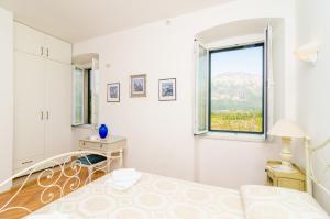 a white bedroom with a bed and a window at Stone House DiMaTo in Gruda