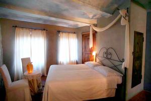 ein Schlafzimmer mit einem weißen Bett und einem Stuhl in der Unterkunft Dindina Agriturismo in Neviglie