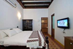 a bedroom with a bed and a flat screen tv at Hospedaria Abrigo De Botelho in Panaji