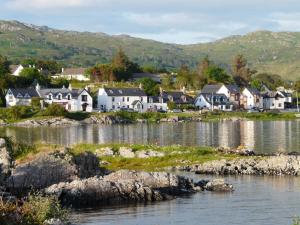 a row of houses on the shore of a body of water at Arisaig Holiday Apartment in Arisaig