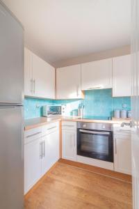 una cocina con armarios blancos y un aparato de acero inoxidable en The Cluthar - Ground Floor West End City Centre Rockvilla flat & Parking, en Glasgow
