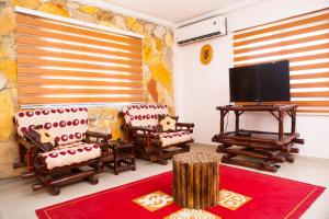 a living room with chairs and a flat screen tv at Maxwell Court Apartments in Accra