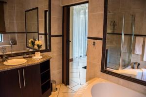 een badkamer met een bad, een wastafel en een douche bij Casa Flora Guesthouse in Pretoria