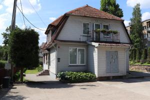 uma pequena casa branca com uma varanda numa rua em Nileja em Vilnius