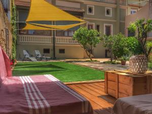 a patio with a lawn and a yellow umbrella at Ca l'Esparrech in Malgrat de Mar