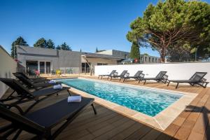 una piscina con tumbonas junto a un edificio en ibis Carcassonne Est la Cité, en Carcassonne