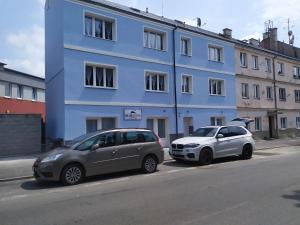 dwa samochody zaparkowane przed niebieskim budynkiem w obiekcie Bluestars Family w Karlowych Warach