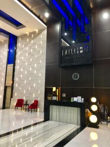 a lobby with a waiting area with red chairs and a sign at Trillium Apartment - Cozy and Bright Downtown Surabaya by Le Ciel Hospitality in Surabaya