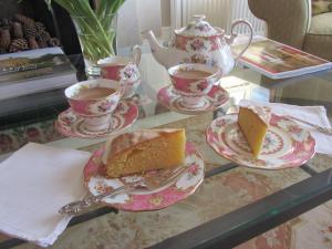 a table with tea and a piece of cake and tea cups at Anne’s House in Hastings