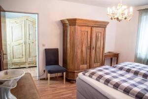 a bedroom with a bed and a chair and a cabinet at Ferienwohnungen im Dorfwirt in Blaichach