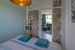 een slaapkamer met een bed met twee blauwe handdoeken erop bij Amsterdam Beach Apartment 65 in Zandvoort