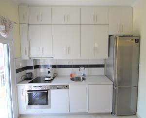 a kitchen with white cabinets and a stainless steel refrigerator at Emotion Apartments in Asprovalta