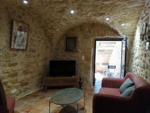 een woonkamer met een tv in een stenen muur bij Gîte d'Emeline in Bourdic