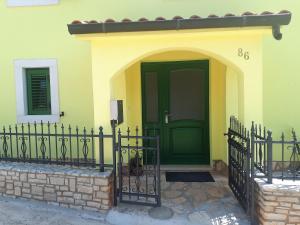 una puerta verde en una casa amarilla con una valla en Apartment Terra Rossa, en Kaštelir