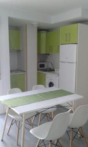 ロケタス・デ・マルにあるBersan2のキッチン(緑のキャビネット、テーブル、椅子付)