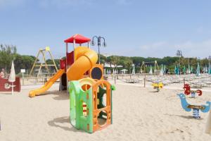 un parque infantil con tobogán y equipo de juegos en la arena en VILLA CRISTINA N.05, en Lido di Jesolo