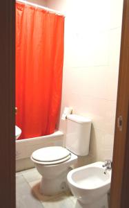 ein Badezimmer mit einem WC und einem orangefarbenen Duschvorhang in der Unterkunft Apartamento Feria 2 in Sevilla