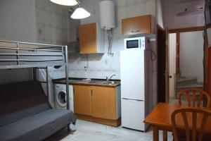 eine kleine Küche mit einem weißen Kühlschrank und einem Tisch in der Unterkunft Apartamento Feria 2 in Sevilla