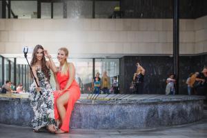 dwie kobiety siedzące obok siebie przed fontanną w obiekcie Bluestars Family w Karlowych Warach