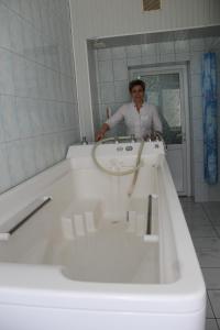 a woman standing in front of a white bath tub at Zheleznovodskaya Klinika Sanatorium in Zheleznovodsk
