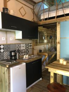 - une cuisine avec des armoires noires et un réfrigérateur blanc dans l'établissement Le domaine des hauts de canche Magnifique Tiny house avec Spa, à Étaples