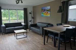 a living room with a couch and a table and chairs at Chalets It Wiid in Eernewoude