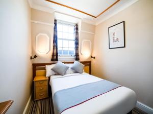 a small bedroom with a bed and a window at Vegas Hotel in London