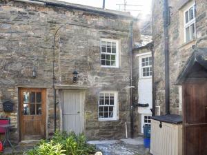 an old stone building with a white door and windows at secret cottage in Sedbergh