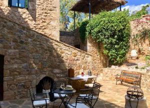 un patio con tavoli, sedie e un muro in pietra di Villa Vager Mani Hotel a Kalamáta