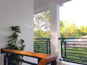 Za Priscila Tourist Inn في أندا: مقعد خشبي على شرفة مع نافذة