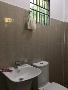 La salle de bains est pourvue de toilettes blanches et d'un lavabo. dans l'établissement Za Priscila Tourist Inn, à Anda