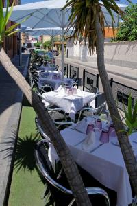 a group of tables and chairs with palm trees at Hotel Vivar in Griñón