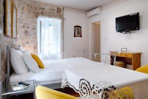 1 dormitorio con 1 cama y TV en la pared en Villa Kuljis, en Komiža