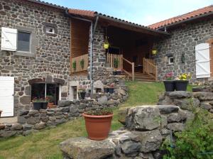 a stone house with a stone wall and a yard at La freycenette in Arlempdes
