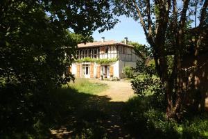 Ein altes Haus wird durch die Bäume gesehen in der Unterkunft Ricouch, chambre d'hôtes et permaculture in Momuy