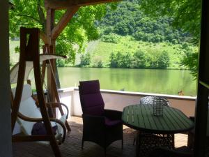une terrasse couverte avec une table et des chaises et une vue sur le lac. dans l'établissement Moselidyll, à Traben-Trarbach