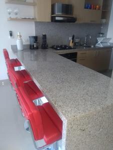 a kitchen with two red chairs at a counter at Apartamentos Reserva del Mar in Santa Marta
