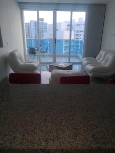 a living room with two chairs and a large window at Apartamentos Reserva del Mar in Santa Marta