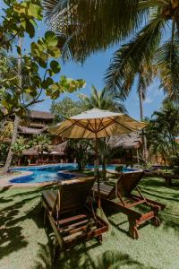 duas cadeiras e um guarda-sol junto a uma piscina em Dayo Hotel em Flecheiras
