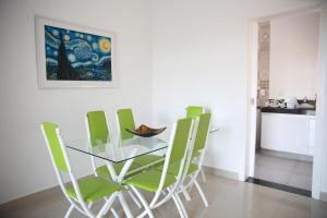 uma sala de jantar com uma mesa de vidro e cadeiras verdes em Apartamento novo 3 quartos em Diamantina