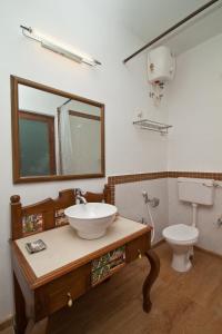 a bathroom with a sink and a toilet and a mirror at Hospedaria Abrigo De Botelho in Panaji