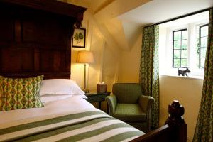 a bedroom with a bed and a chair and a window at The Lamb Inn in Burford