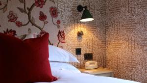 a bedroom with a bed with a red pillow and a lamp at The Lamb Inn in Burford