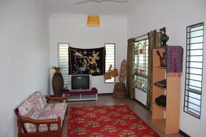 a living room with a couch and a tv at Marco Polo Rest House in Kuching